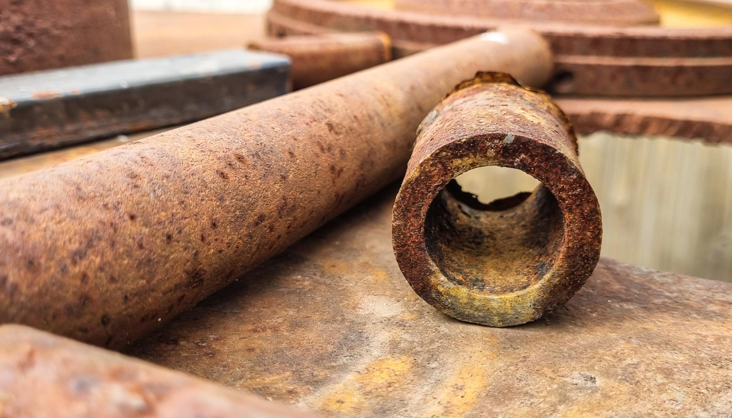 Close-up of rusty metal pipes and surfaces, showing corrosion and texture in an industrial setting.